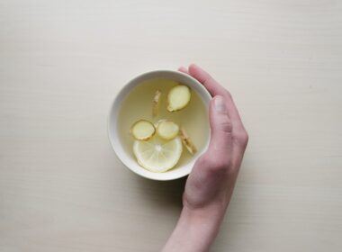 person holding white bowl with sliced lime and ginger inside